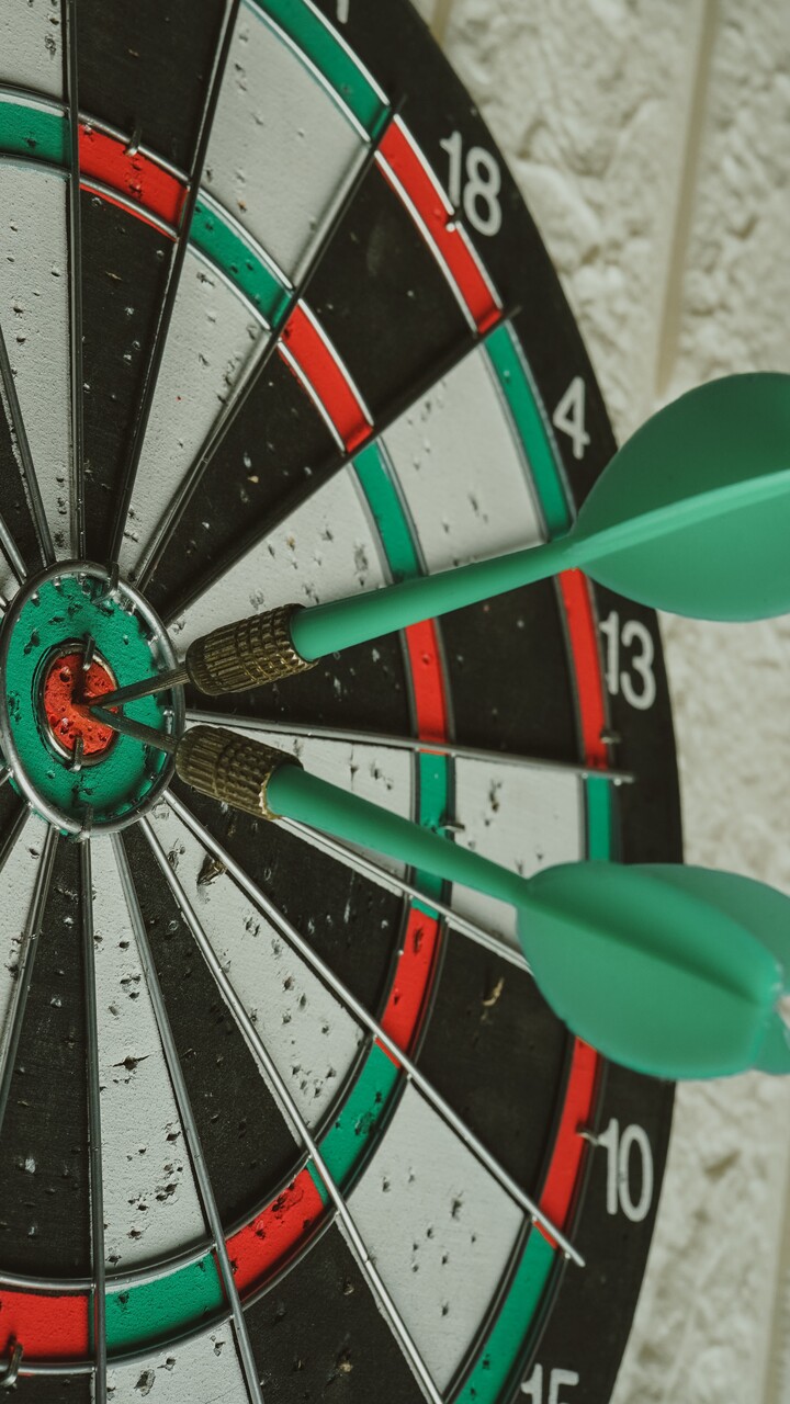 Darts Zielscheibe in rot, gr&uuml;n, schwarz und wei&szlig; mit zwei Pfeilen in der Mitte.